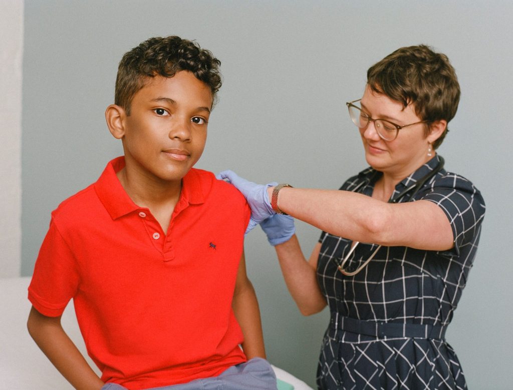 Young boy receives a vaccination from a smiling healthcare professional.