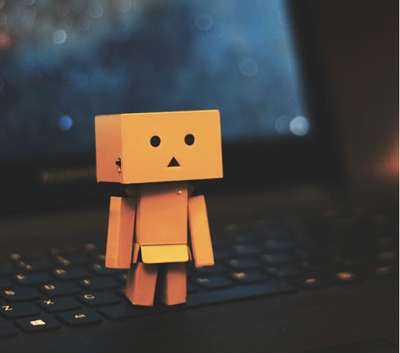 Posed photograph showing a small toy robot standing on the keys of a laptop computer. Image credit: Jem Sahagun/Unsplash