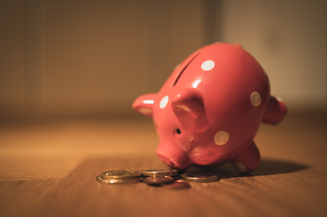 Pink piggy bank with white polka dots, tipped over a small pile of coins. Image credit: Andrew Taissin/Unsplash