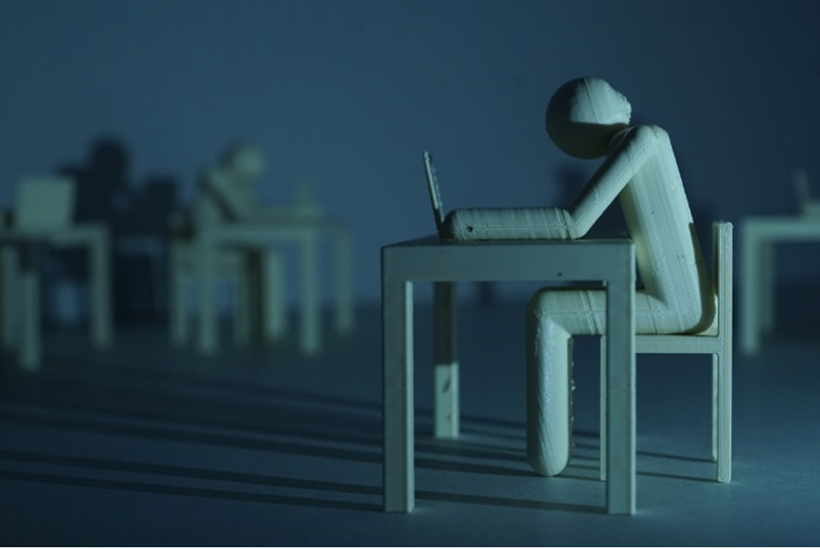 Plastic figure resembling a human who sits on a table infront of a laptop in a dark room. Long shadows disseminate a gloomy mood. Image credit: Max Gruber / Better Images of AI / Clickworker 3d-printed / CC-BY 4.0