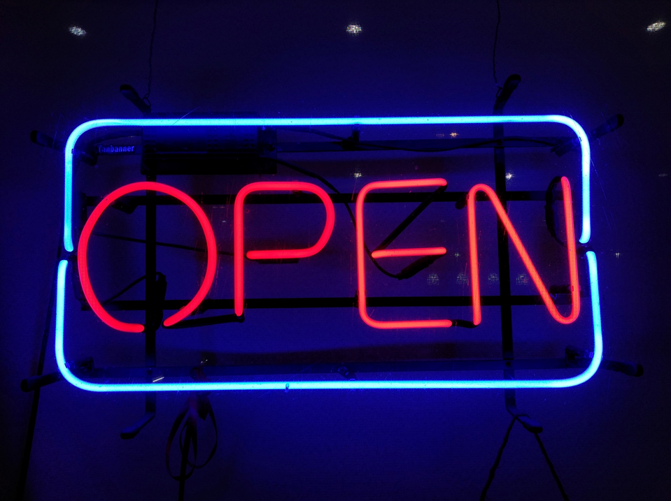 Red and blue neon “open” sign in a window. Image credit: Shark Ovski/Unsplash