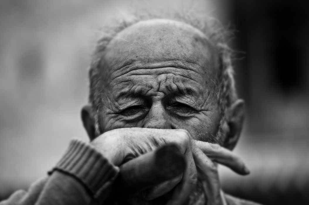 Black and white photograph of an older man, with sad or pensive look on his face, hand to his mouth as if in deep thought. Image credit: Rad Cyrus/Unsplash