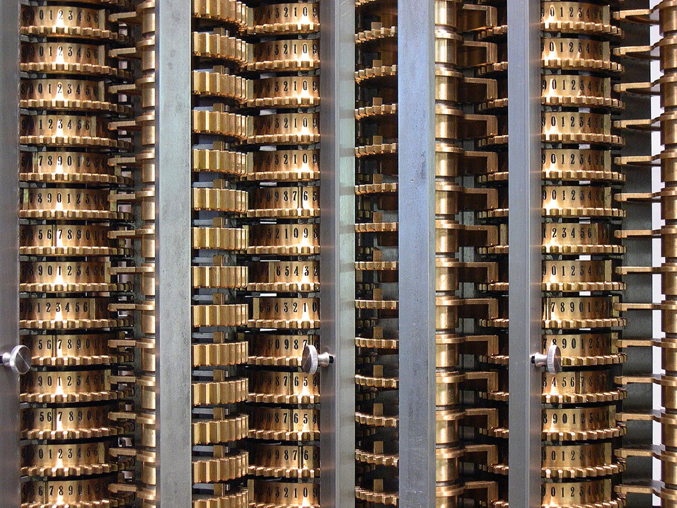 “Closeup of the London Science Museum's difference engine showing some of the number wheels and the sector gears between columns. The sector gears on the left show the double-high teeth very clearly. The sector gears on the middle-right are facing the back side of the engine, but the single-high teeth are clearly visible. Notice how the wheels are mirrored, with counting up from left-to-right, or counting down from left-to-right. Also notice the metal tab between "6" and "7". That tab trips the carry lever in the back when "9" passes to "0" in the front during the add steps (Step 1 and Step 3).” Image and description credit: Carsten Ullrich/Wikipedia (CC BY-SA 2.5).