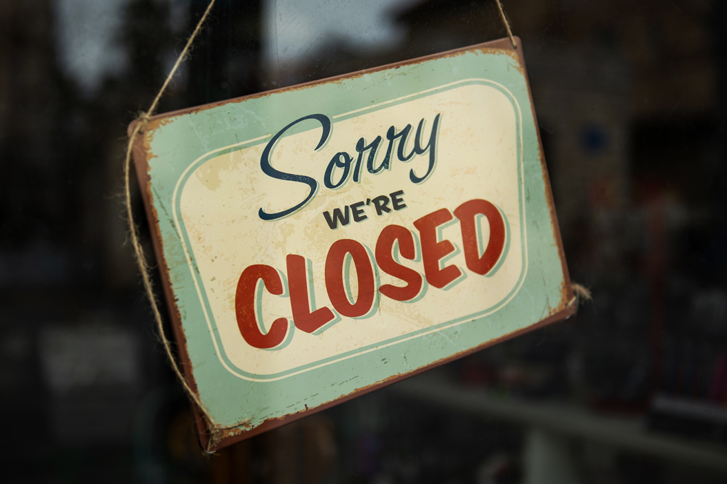 Closeup photograph of a sign hanging in a glass doorfront that says “Sorry we’re closed.” Image credit: Tim Mossholder/Unsplash