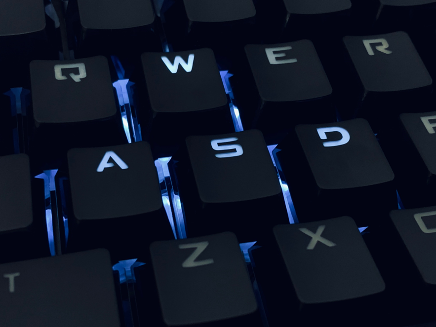 Close-up photograph of a backlit computer keyboard, lit with blue light. Image credit: Muha Ajjan/Unsplash