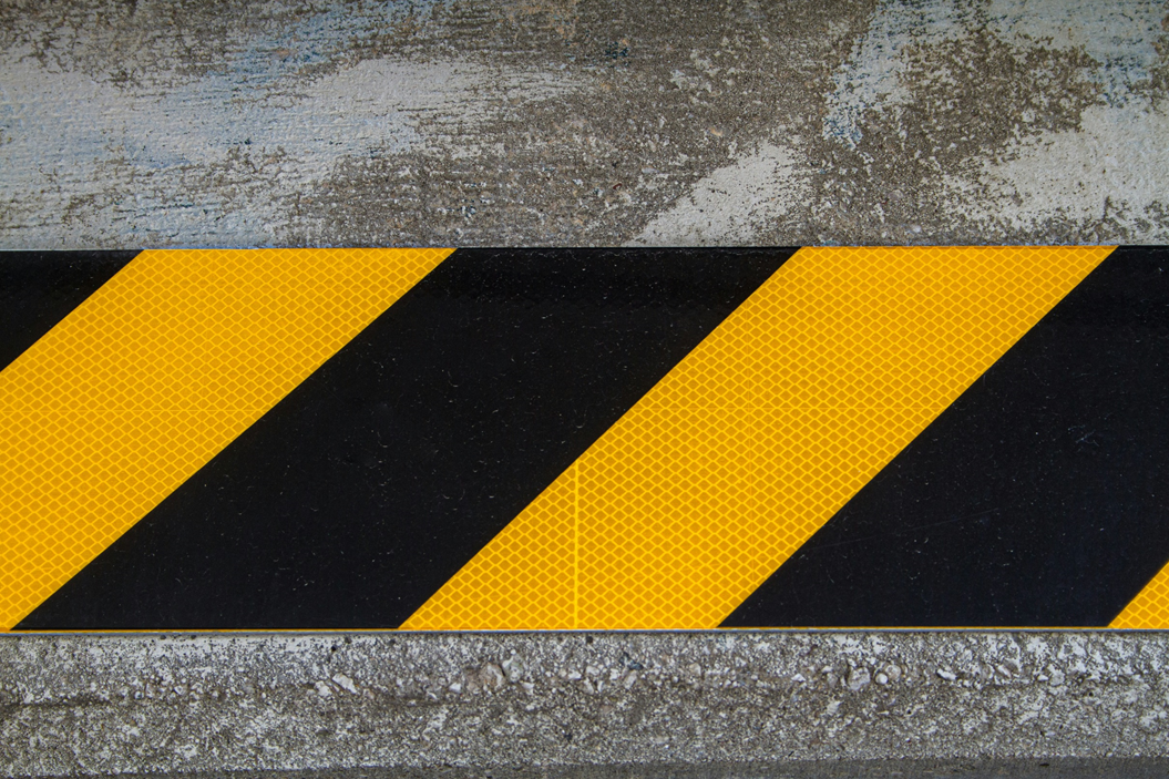 Black and yellow striped traffic caution indicator on concrete pavement. Image credit: Jerrod Erbe/Unsplash