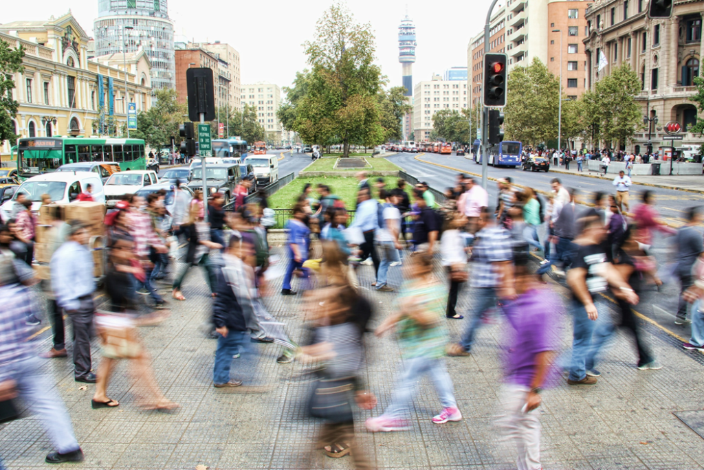 Motion-blurred photograph of a crowd of people crossing a median on a busy city street. Image credit: Mauro Mora/Unsplash