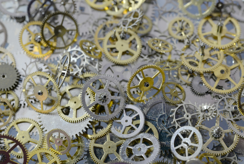 Disorderly heap of metal gears and sprockets of different sizes, some silver, some gold-colored. Image credit: Laura Ockel/Unsplash