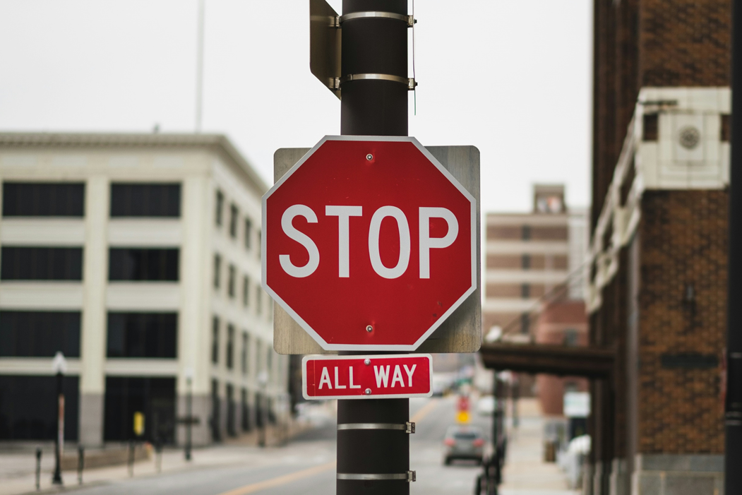 Photograph of a stop sign at a four-way city intersection. Image credit: John Matychuk/Unsplash