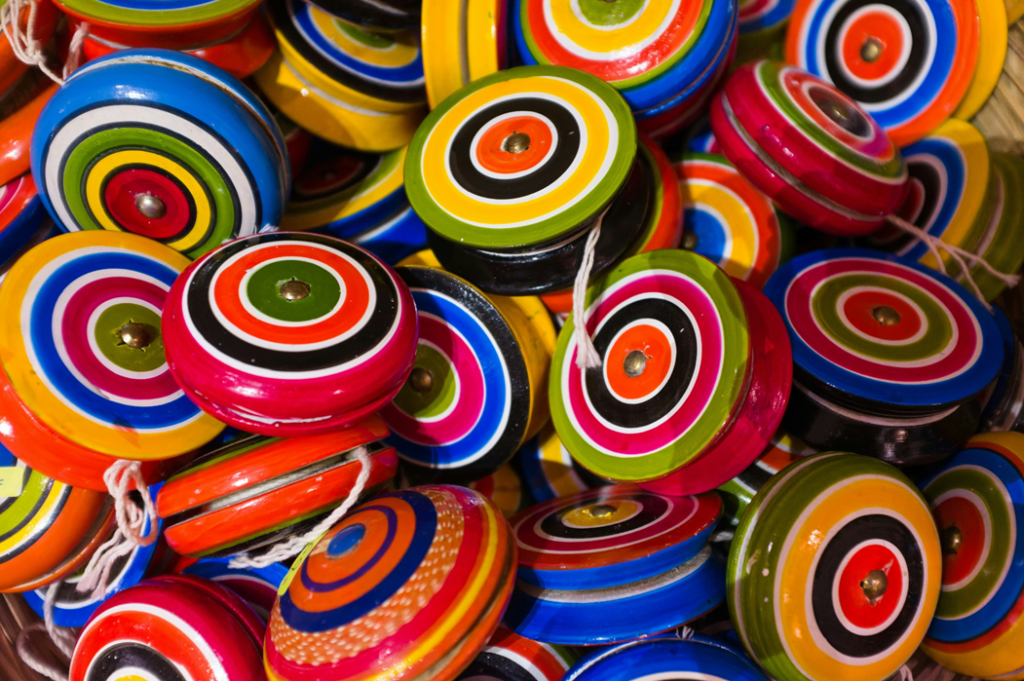 A disorderly heap of colorful wooden yo-yos, painted with concentric circle designs in different bright colors. Image credit: Eric Prouzet/Unsplash