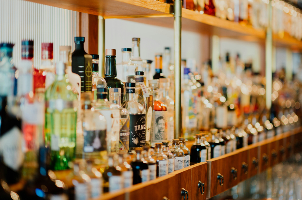 Rows of liquor bottles in illuminated racks at a bar or restaurant. Image credit: Chuttersnap/Unsplash