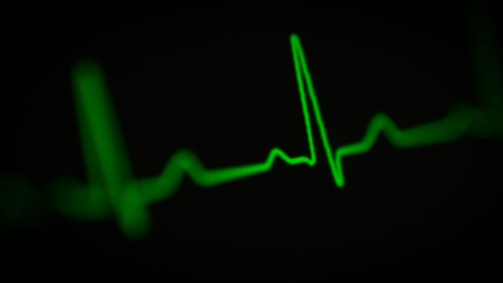 A green glowing electrocardiogram trace on a hospital monitor video screen shows the peaks and depressions of a heart rhythm. Image credit: Joshua Chehov/Unsplash